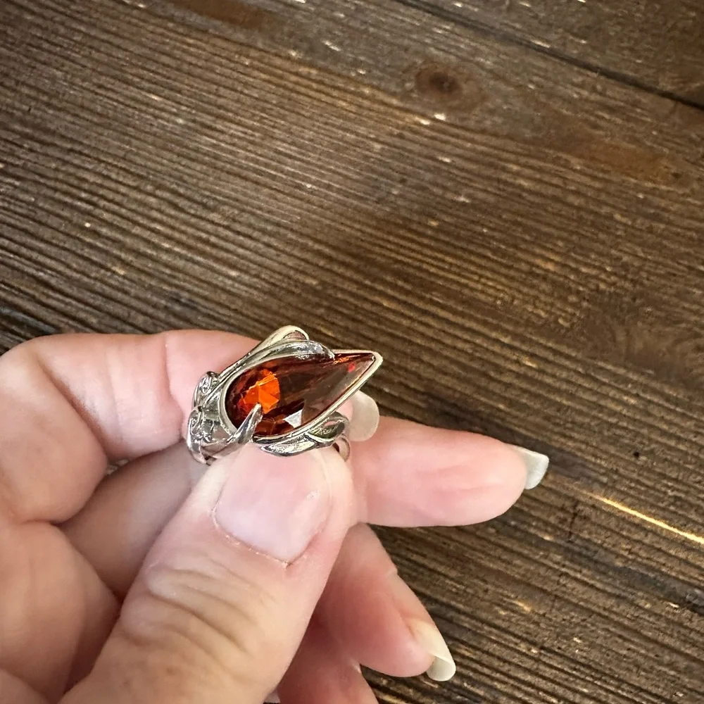 Ring in silver metal intricate with teardrop shaped amber color stone